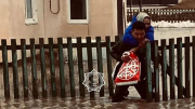 Фото: МЧС РК. Сотрудник МЧС на спине несет женщину через воду, которая затопила дом